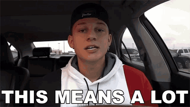 a young man in a car with the words this means a lot behind him