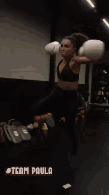 a woman in a black sports bra is throwing a ball in a gym with the hashtag #team paula