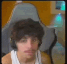 a man wearing headphones is sitting in a chair and making a funny face .