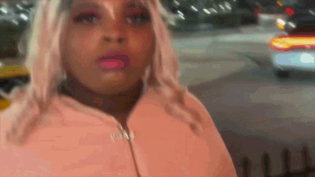 a woman in a pink coat with the word vogue on the front