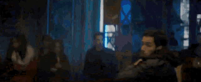 a blurry picture of a man standing in front of a crowd in a dark room .
