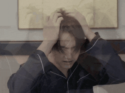 a man in a blue pajama shirt is holding his head