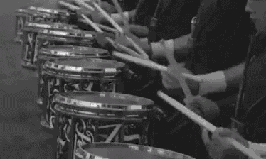 a black and white photo of a marching band playing drums