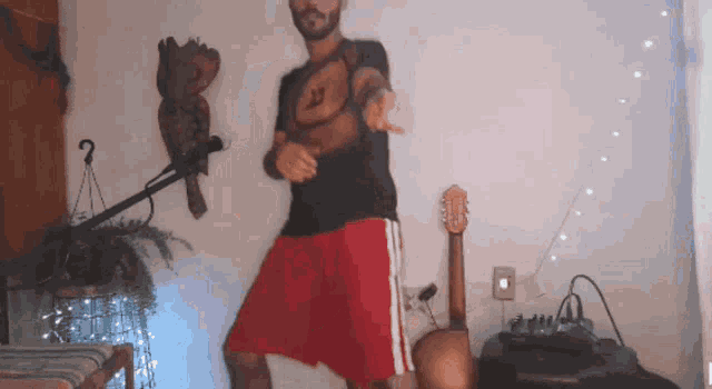 a man is dancing in a room with a guitar and a microphone
