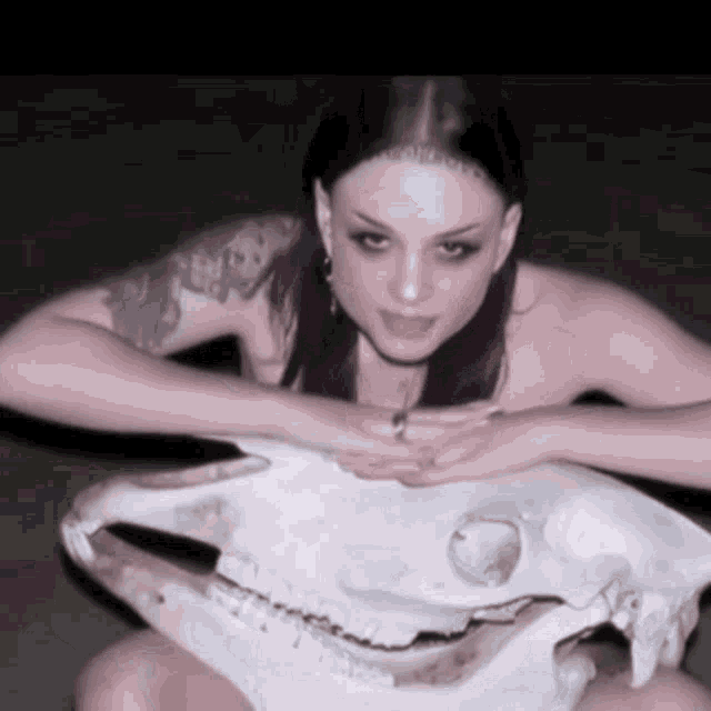 a naked woman with purple hair is holding a skull