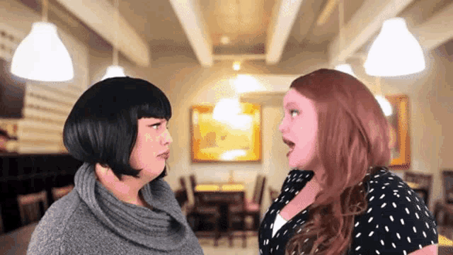 two women are standing next to each other in a room
