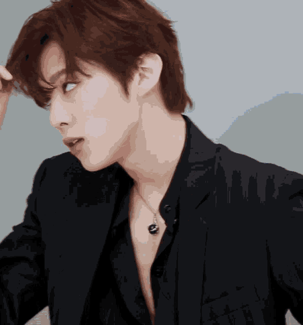 a close up of a man wearing a black jacket and a black necklace