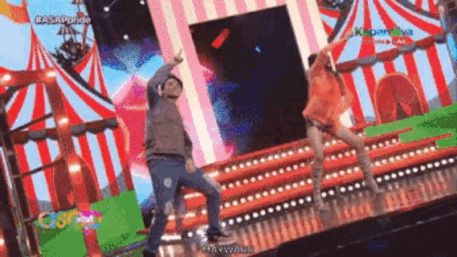 a man and a woman are dancing on a stage with a carnival in the background and the word casa on the bottom