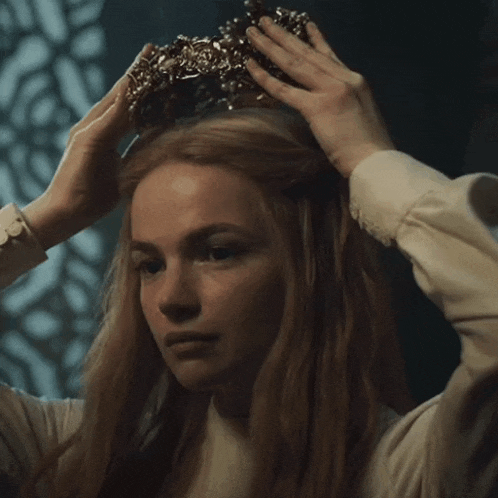 a woman with long red hair is wearing a crown
