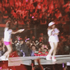 two women are dancing on a stage in front of a crowd and a sign that says ' shoesmith ' at the bottom