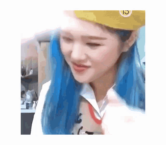 a woman with blue hair and a yellow hat is smiling .