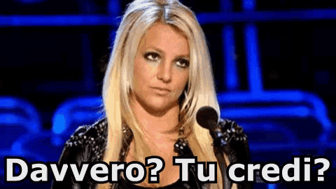 a blonde woman stands in front of a microphone and says davvero tu credi ?