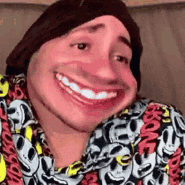 a man wearing a hat and a shirt with mickey mouse faces on it is smiling .