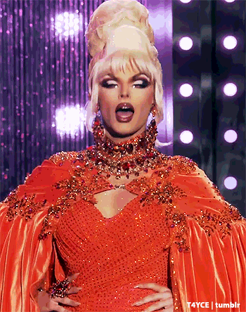 a drag queen is wearing a red dress with a cape