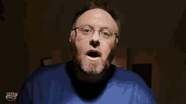 a man with a beard and glasses is wearing a blue shirt that says vape wild on it