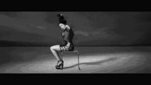 a black and white photo of a woman sitting on a chair in the desert .