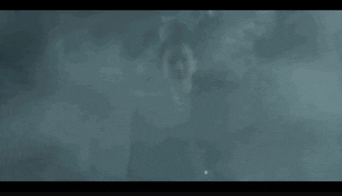 a woman wearing sunglasses and a black tank top is running through a dark room .