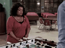a woman in a red shirt is standing in front of a foosball table