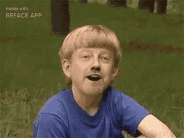 a young boy is sitting in the grass with his mouth open .