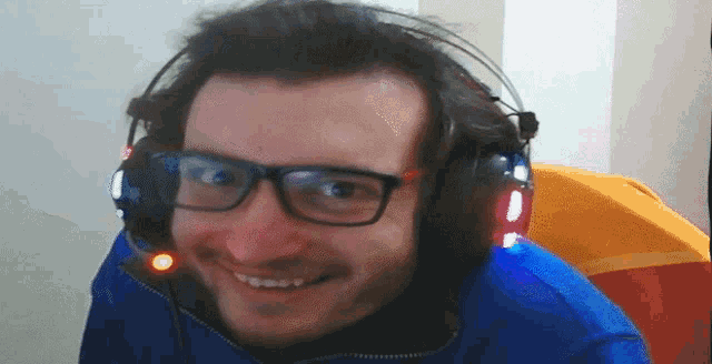 a man wearing glasses and headphones looks at the camera