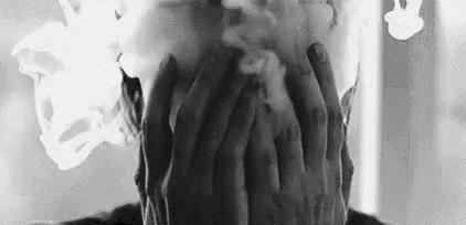 a black and white photo of a person covering their face with smoke coming out of their eyes .