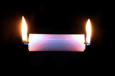 two candles are lit up in the dark and one is purple