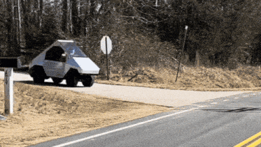 a small white car is driving down a road
