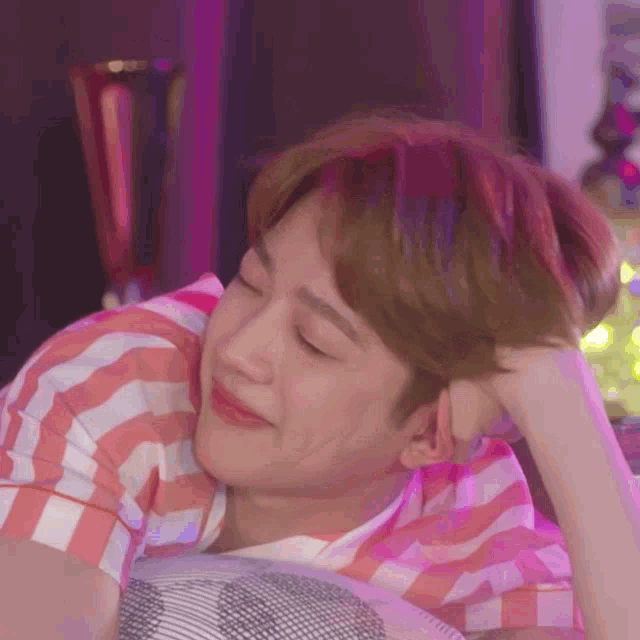 a man in a pink and white striped shirt is smiling