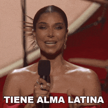 a woman in a red dress is holding a microphone and the words tiene alma latina are above her