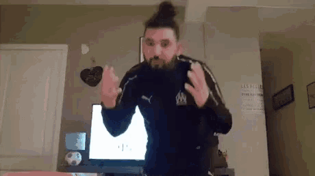 a man with a beard is standing in front of a television .