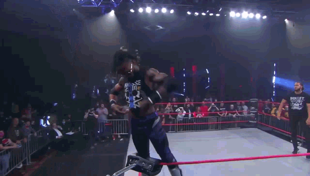 a wrestler wearing a shirt that says bullet club walks out of the ring