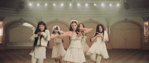 a group of young women in white dresses are dancing on a stage