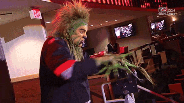 a man with green paint on his face and a red exit sign