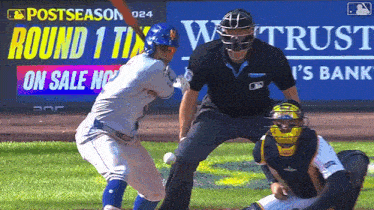 a baseball game is being played in front of a sign that says postseason round 1 on sale now