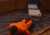 a man in an orange prison uniform is laying on the floor .