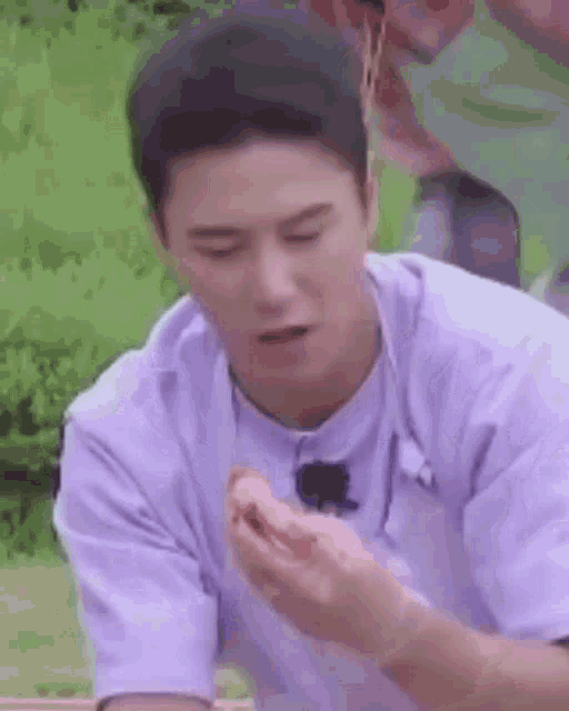 a man in a white shirt is eating a piece of food from his hand .