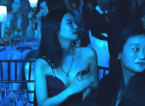 a woman in a black dress with a pearl necklace is clapping