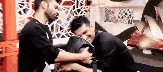 two men are hugging each other and one of them is holding another man 's head .