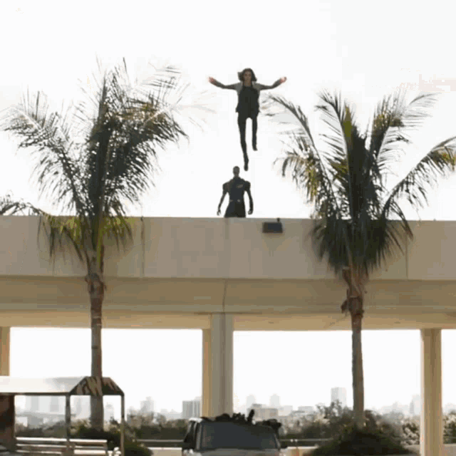 a man is jumping off a bridge while another man stands on the side
