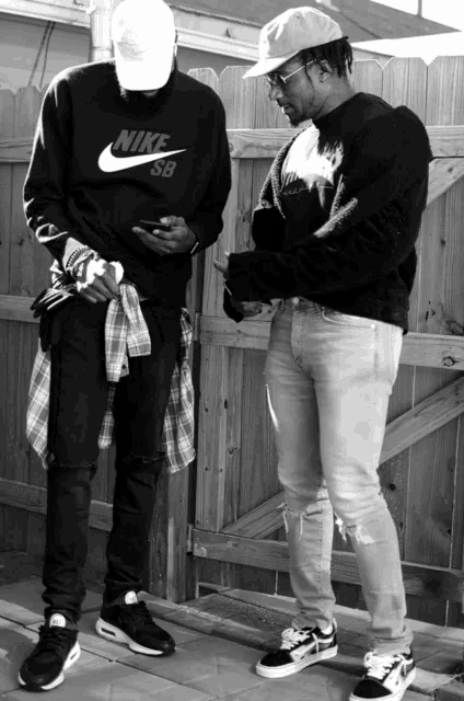 a man wearing a nike sweatshirt stands next to another man