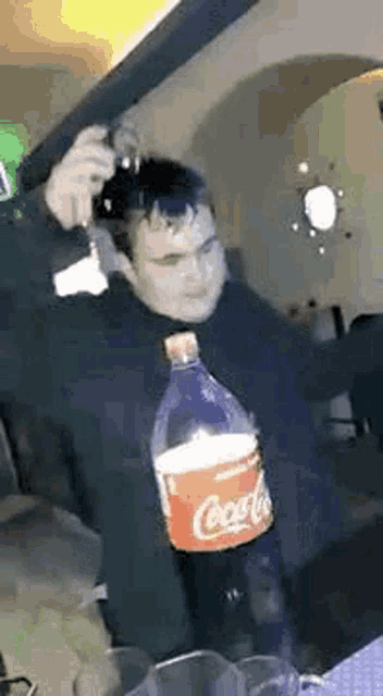 a man is holding a gun and a bottle of coca cola .