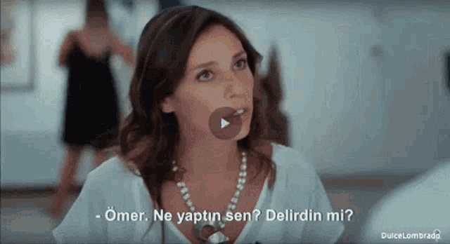 a woman in a white shirt and pearl necklace is talking to a man in a black dress ..