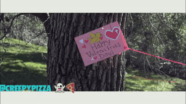 a pink sign that says happy valentine 's day is tied to a tree
