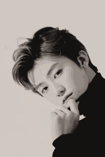 a black and white photo of a young man with his hand on his face