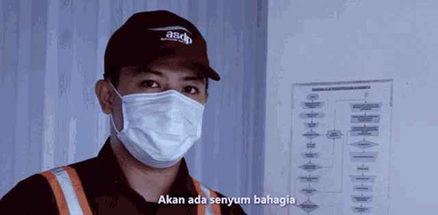 a man wearing a mask and a asdp hat says akan ada senyum bahagia
