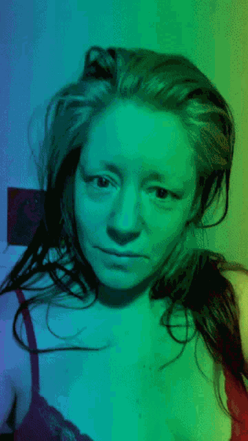 a woman 's face is lit up with green and blue light