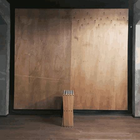 a wooden stool sits in front of a large wall