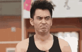 a man in a black tank top is making a face .