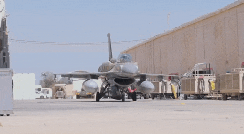 a fighter jet is parked in front of a warehouse