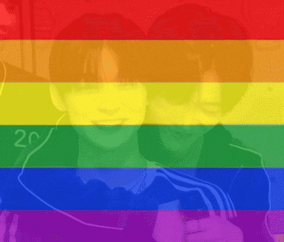two people are hugging in front of a rainbow flag